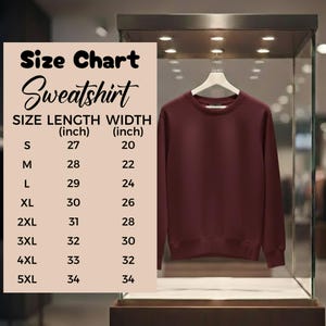 May include: A maroon sweatshirt hangs on a white hanger inside a glass display case. A size chart is displayed to the left, detailing length and width measurements in inches for sizes S through 5XL.
