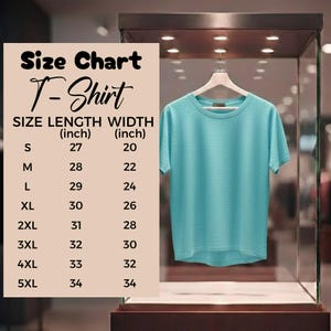 May include: A light blue T-shirt displayed on a hanger inside a glass case. A size chart is visible, detailing shirt sizes from S to 5XL, with length and width measurements in inches. The shirt has a crew neck and short sleeves.