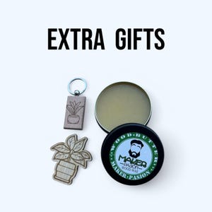 May include: Image featuring a collection of gifts. Includes a wooden keychain and a wooden plant-shaped cutout. Also shown are two containers of wood wax, one open and one closed, with the text "EXTRA GIFTS" at the top.