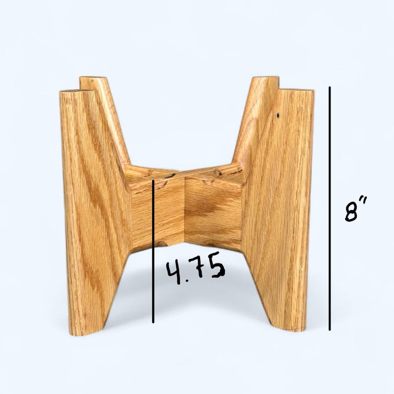 May include: A wooden plant stand with a natural finish. The stand is 8 inches tall and 4.75 inches wide. The stand is designed to hold a potted plant. The stand has a mid-century modern design.