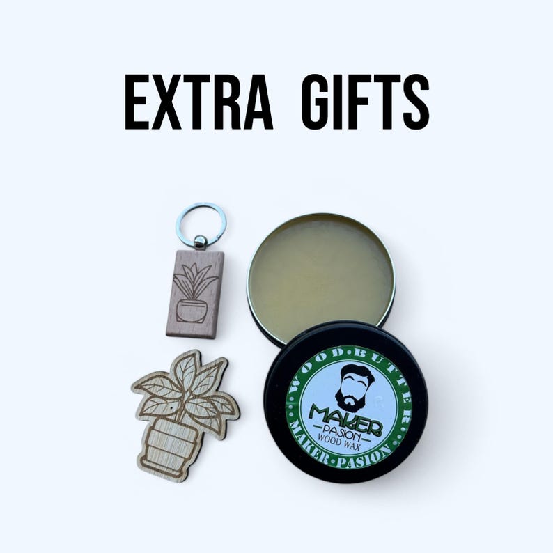 May include: An assortment of gifts, including a wooden keychain and a plant-shaped wooden cutout. A small, open tin of wood butter and a black tin of Maker Pasion wood wax are also visible. The text "EXTRA GIFTS" is at the top.