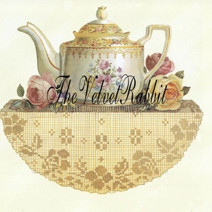May include: A vintage porcelain teapot with floral designs sits on a delicate lace doily. The teapot has a gold trim and is decorated with pink, yellow, and blue flowers. The doily is a light brown color and has a scalloped edge.