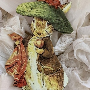 Pode incluir: Um recorte de madeira do Peter Rabbit do livro infantil de Beatrix Potter. O recorte é pintado com uma ilustração detalhada do Peter Rabbit usando um chapéu verde e segurando uma maçã.