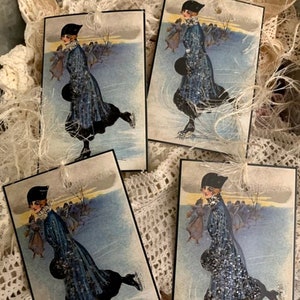 May include: Four vintage Christmas gift tags featuring a woman ice skating in a blue dress and black hat. The tags have a white background with a blue and white winter scene.