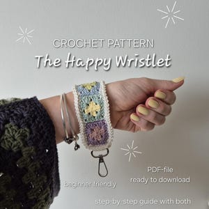 May include: A crocheted wristlet with a floral design in pastel colors is displayed on a wrist. The wristlet is attached to a silver clasp. Text on the image reads "CROCHET PATTERN The Happy Wristlet" and "beginner friendly, ready to download".
