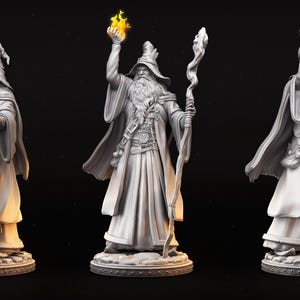 May include: A detailed figurine of a wizard in a long robe and hat, holding a staff and a flame. The wizard has a long beard and is standing on a circular base. The figure is a light gray color.