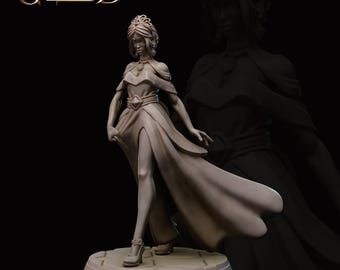 May include: A white painted miniature figurine of a woman wearing a long flowing gown and a crown. The figurine is standing on a circular base.
