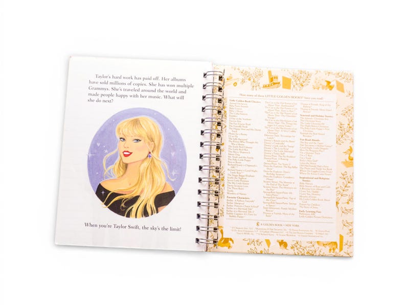 May include: Open book with a spiral binding featuring an illustration of a blonde woman in a black top. Text on the left page reads "When you're Taylor Swift, the sky's the limit!" The right page lists titles.