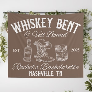 May include: Brown fabric banner with white text and illustrations. The banner reads "Whiskey Bent & Veil Bound" with a whiskey bottle, cowboy boot, and cocktail glass. "Rachel's Bachelorette Nashville, TN" is also displayed.