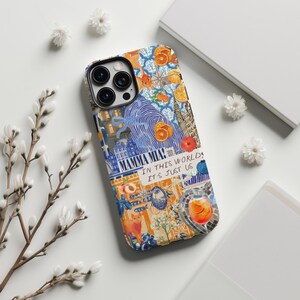 Puede incluir: Una funda de teléfono colorida con un diseño de collage que incluye naranjas, edificios y el texto "MAMMA MIA! IN THIS WORLD IT'S JUST US." La funda tiene un recorte negro para la cámara y un acabado brillante.