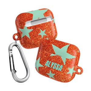 May include: Two red glitter AirPod cases with a mint green star pattern. One case has the name "ALYSSA" printed on it. A silver carabiner clip is attached to one of the cases.