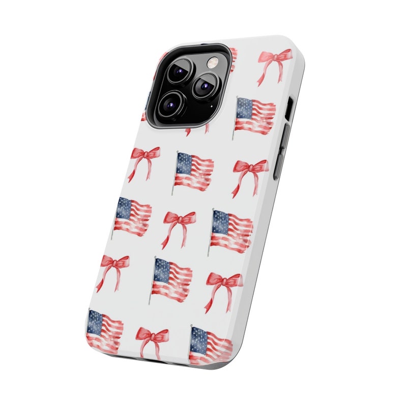 May include: White phone case with a pattern of red, white, and blue American flags and red bows.
