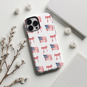 May include: A white phone case with a repeating pattern of red, white, and blue American flags and red bows.