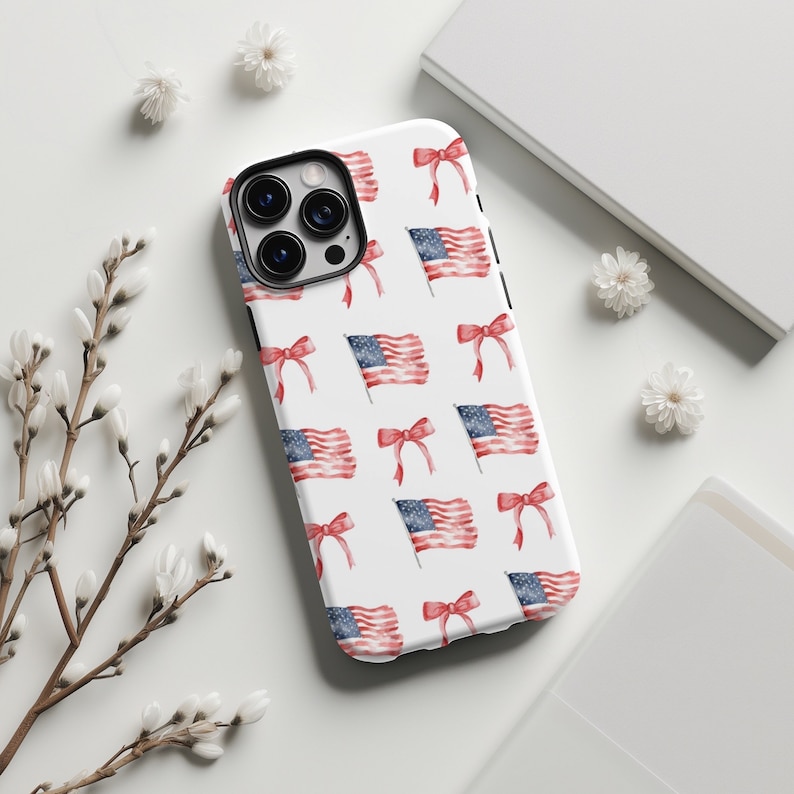 May include: A white phone case with a repeating pattern of red, white, and blue American flags and red bows.