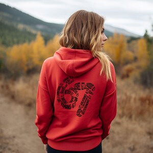 May include: A red hoodie with a hood and long sleeves. The back of the hoodie features a black graphic design with the text "Ezekiel 6:7" and other biblical references arranged in a circular pattern. The hoodie is made of a soft material.