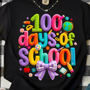 May include: Black t-shirt with a colorful, textured graphic celebrating "100 days of school." The design includes the number 100, the words "days of school," and school-themed elements like pencils, flowers, and a globe.