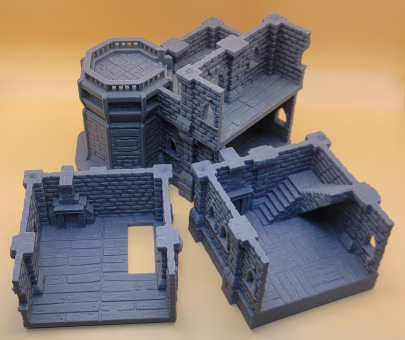 May include: A gray, 3D-printed modular dungeon building set featuring stone brick walls, a fireplace, a staircase, and an octagonal tower section. The set consists of three separate, interlocking pieces with detailed floor textures and open doorways.