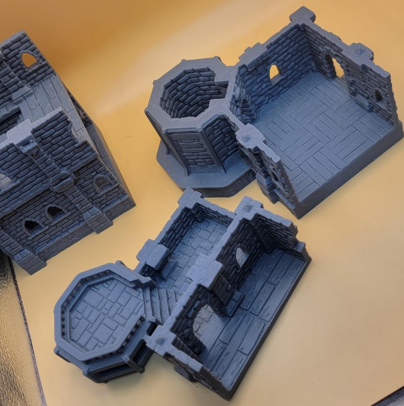 May include: Three gray, unpainted miniature building structures featuring detailed stone brick textures, arched window openings, and open floor plans. These modular pieces include a tall tower section and two lower, rectangular room segments with stone flooring.