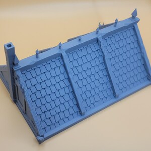May include: A light blue miniature building roof section featuring a textured shingle pattern, a tall chimney on the left side, and decorative finials along the ridge line. The structure is molded in a single color with visible panel seams.