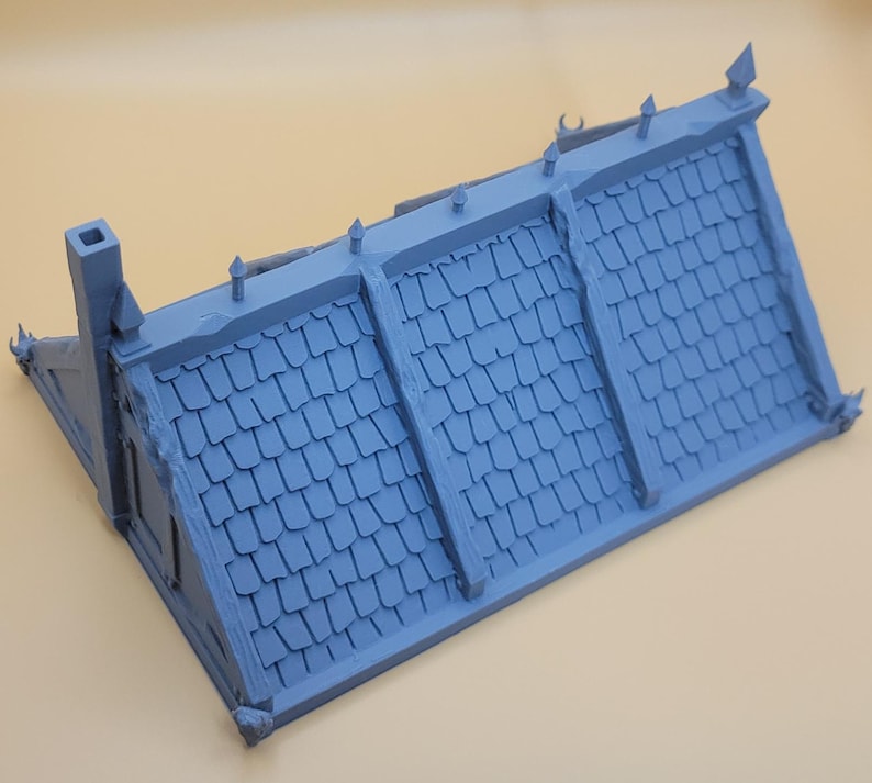 May include: A light blue miniature building roof section featuring a textured shingle pattern, a tall chimney on the left side, and decorative finials along the ridge line. The structure is molded in a single color with visible panel seams.