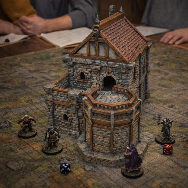 May include: A miniature stone building model with a brown tiled roof and wooden trim, featuring a multi-level structure with a balcony. Four small painted character figurines and two multi-sided dice are positioned on the grid-patterned base.