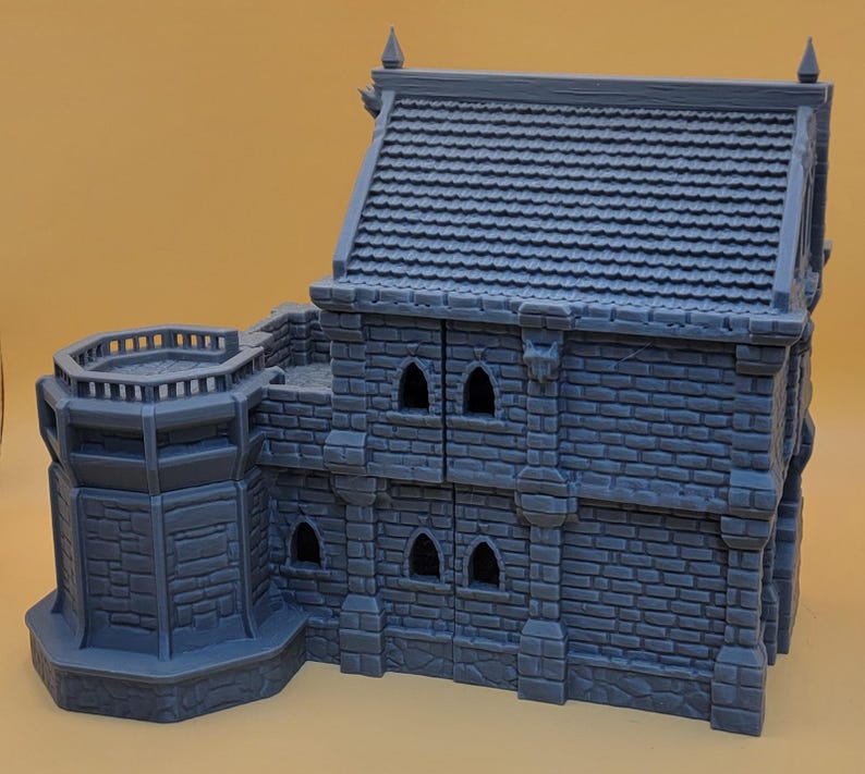 May include: A gray, 3D-printed miniature building featuring a two-story stone structure with a tiled roof, a side tower with a balcony, and multiple arched window openings. The model displays detailed brickwork textures across the exterior walls.