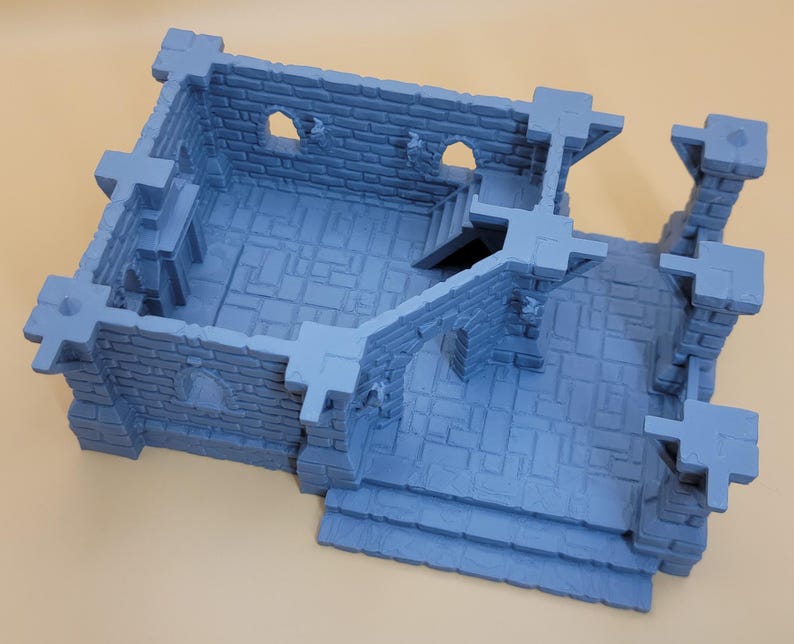 May include: A light blue, 3D-printed miniature stone building structure featuring a rectangular room with brick-textured walls, arched window openings, a small staircase leading to an upper level, and an open-air courtyard area with stone flooring.