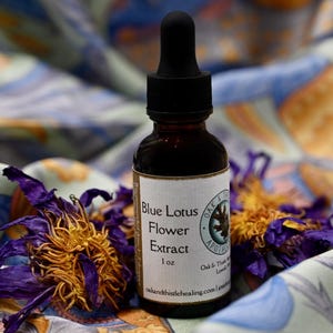 May include: A dark amber glass bottle with a black dropper, labeled "Blue Lotus Flower Extract 1 oz." The label also includes the text "Oak & Thistle Apothecary." Dried blue lotus flowers are in the foreground.