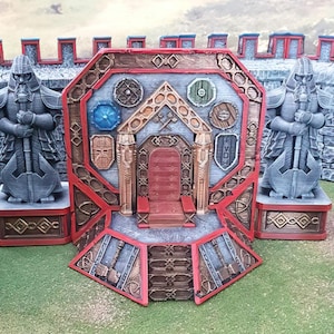 Könnte beinhalten: Ein 3D-gedrucktes Miniatur-Schlosstor mit einer roten Holztür, zwei steinernen Statuen, die Äxte halten, und einem roten und goldenen Thron mit einem roten Kissen. Das Tor ist mit Schilden und Äxten verziert.
