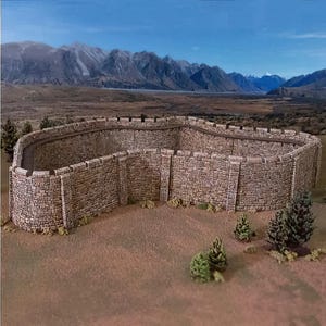 May include: A model of a stone fortress with a curved wall and crenellations. The fortress is made of light brown stones and sits on a brown surface with small green trees. Mountains and a blue sky are in the background.