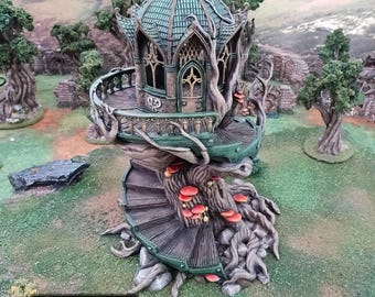May include: A detailed miniature fantasy treehouse with a spiral staircase, balcony, and domed roof. The structure is primarily green and brown, with red mushroom accents. The base of the treehouse features the text "PRINTABLE SCENERY" and the website address.