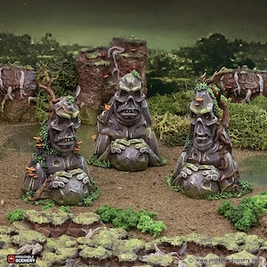May include: Three grey, moss-covered statues with skull-like faces and holding round objects. The statues are surrounded by green moss and foliage, with a forest backdrop. The statues have tree-like features, with branches and fungi.