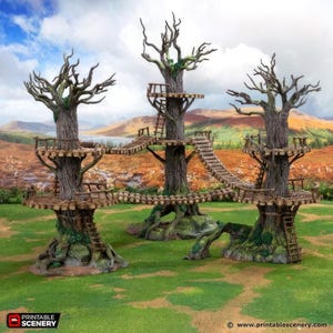 Op de afbeelding: Een gedetailleerde tabletop gaming terreinset met drie grote, verweerde bomen met meerdere platforms en touwbruggen. De bomen hebben ingewikkelde schorsstructuren, ladders en platforms, tegen een achtergrond van een grasveld en een ver landschap.