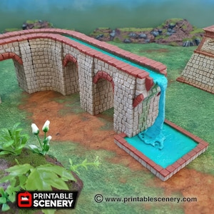 May include: A miniature stone bridge with a waterfall feature. The bridge has a brick-red trim and arches, with a light blue water channel. The waterfall flows into a small pool. The scene is set on a brown and green terrain.