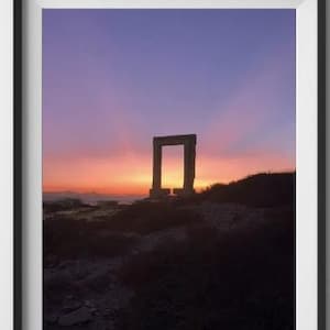 May include: A framed photograph of a stone archway silhouetted against a vibrant sunset sky. The sky is a mix of pink, purple, and orange hues. The archway is in the foreground, with a grassy hill in the background.