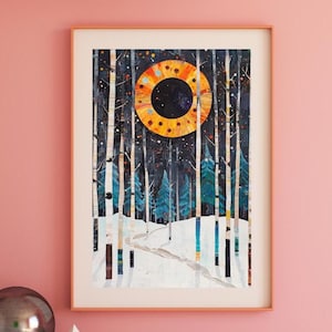 May include: A framed print of a winter forest scene with a large, orange and yellow sun in the sky. The trees are tall and slender, and the ground is covered in snow. The print is set against a pink wall.