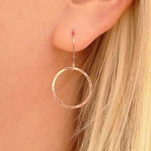 May include: A pair of rose gold hoop earrings with a hammered finish. The earrings are simple and elegant, and would make a great gift for any occasion.