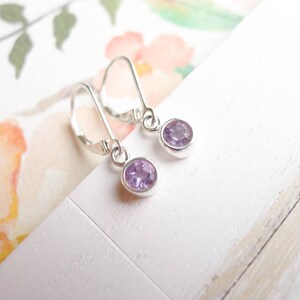 May include: A pair of silver dangle earrings with small, round, light purple gemstones.