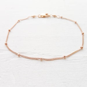 May include: A delicate rose gold chain anklet with small round beads.