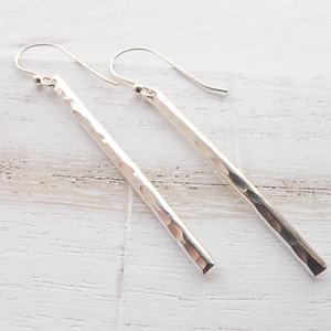 May include: A pair of silver hammered bar earrings with a hook closure.