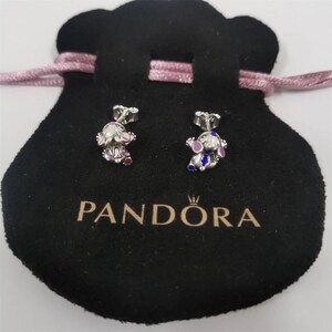 May include: Silver stud earrings with a cartoon character design, featuring pink, purple, and blue enamel details. The earrings are presented on a black velvet pouch, with the "PANDORA" logo visible.