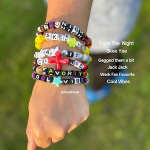 May include: A close-up of a person's wrist wearing five colorful beaded bracelets with letter beads spelling out the phrases "Took The Night", "Skee Yee", "Gagged them a bit", "Jack Jack", "Werk Fan Favorite", and "Cool Vibes".