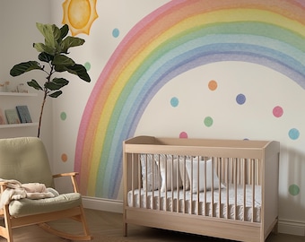 May include: A nursery room featuring a large watercolor-style rainbow wall decal with a yellow sun and multicolored polka dots. The room includes a light wood crib with white bedding, a sage green rocking chair, and a natural fiber area rug.