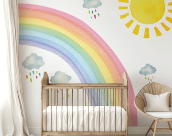 May include: A nursery wall decal set featuring a large, flipped rainbow with pastel colors, a medium-sized sun with yellow rays, and a set of clouds with raindrops. The decals are shown on a white wall with a crib and a wicker chair in the foreground.