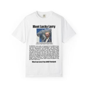 May include: White t-shirt with the text "Meet Lucky Larry" and a photo of a man in a suit. The text below the photo details a story about the man and the 9/11 attacks.