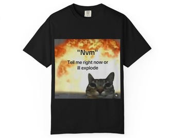 May include: Black t-shirt featuring a meme with a cat and an explosion background. The text on the shirt reads "Nvm" and "Tell me right now or ill explode". The cat has a serious expression.