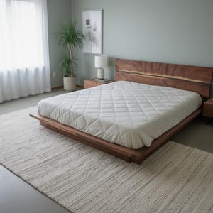 K&ouml;nnte beinhalten: Modernes Schlafzimmer mit einem niedrigen Holzbett, einem Kopfteil aus Naturholz und einer wei&szlig;en, gesteppten Matratze. Zwei passende Nachttische mit Lampen flankieren das Bett. Ein cremefarbener Teppich bedeckt den Boden. Ein gro&szlig;es Fenster mit wei&szlig;en Vorh&auml;ngen.