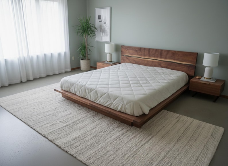 K&ouml;nnte beinhalten: Modernes Schlafzimmer mit einem niedrigen Holzbett, einem Kopfteil aus Naturholz und einer wei&szlig;en, gesteppten Matratze. Zwei passende Nachttische mit Lampen flankieren das Bett. Ein cremefarbener Teppich bedeckt den Boden. Ein gro&szlig;es Fenster mit wei&szlig;en Vorh&auml;ngen.