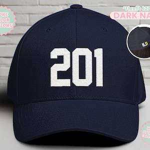 May include: Dark navy baseball cap with the number "201" in white block letters. The cap has a curved brim and the text "Flexfit 6277" and "DARK NAVY" are printed on the top. The cap also has the initials "NJ" embroidered on the side.