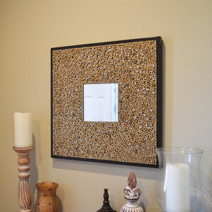 May include: A brown framed mirror with a unique design made of small wooden dowels. The mirror has a white mat and a small rectangular mirror inside.